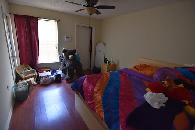 bedroom featuring a ceiling fan, wood finished floors, and a textured ceiling