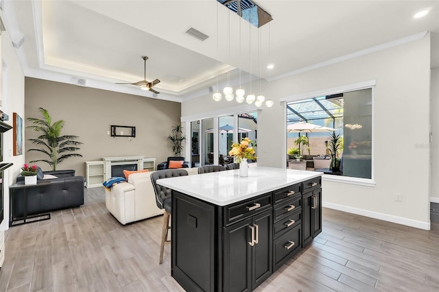 2172 Sherbrook Ave, Davenport, FL 33837 - kitchen featuring a raised ceiling, a kitchen breakfast bar, a ceiling fan, dark cabinetry, and light wood finished floors