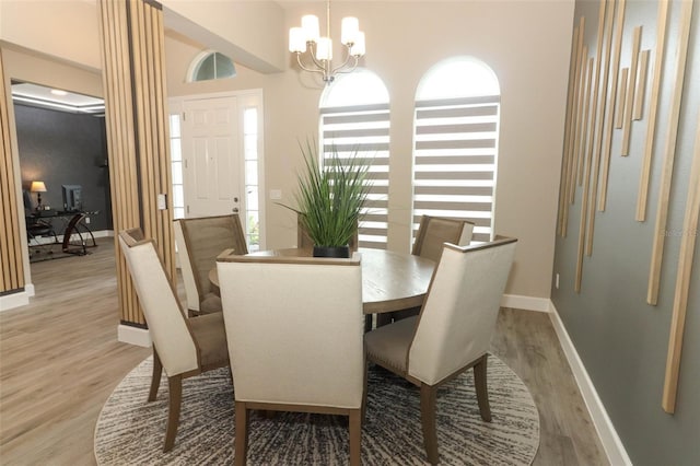 dining area with baseboards, light wood-type flooring, and a notable chandelier