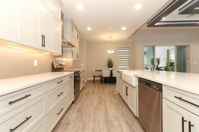 kitchen with light countertops, appliances with stainless steel finishes, a sink, and recessed lighting