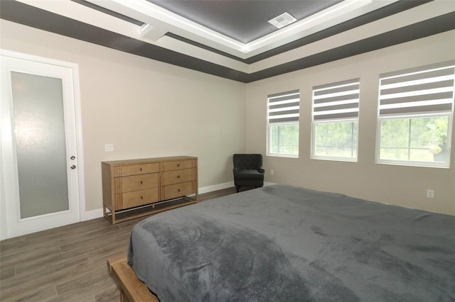 bedroom with visible vents, baseboards, multiple windows, and wood finished floors