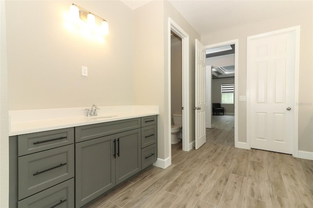 bathroom featuring vanity, baseboards, toilet, and wood finished floors