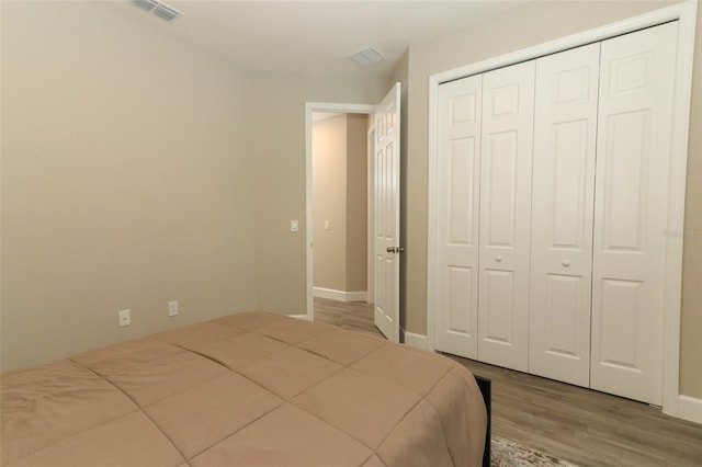 bedroom featuring visible vents, baseboards, a closet, and wood finished floors