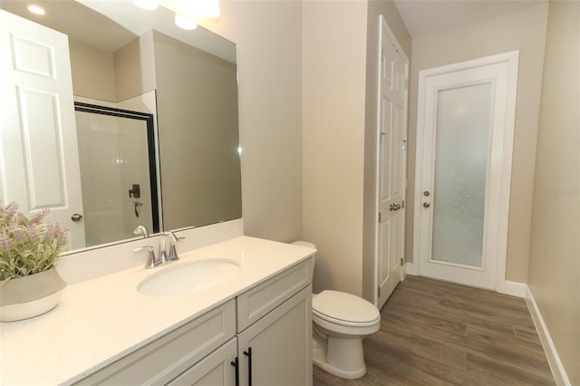 full bath with vanity, toilet, wood finished floors, an enclosed shower, and baseboards