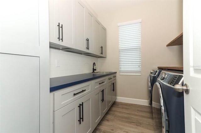 laundry area with baseboards, washer and dryer, a sink, light wood finished floors, and cabinet space