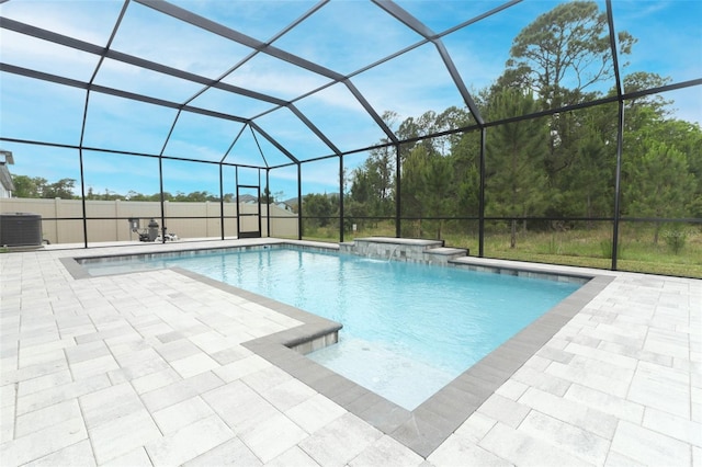 outdoor pool with a jacuzzi, a patio, central air condition unit, and glass enclosure