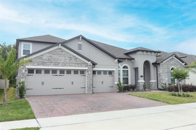 view of front of property with an attached garage, stone siding, decorative driveway, and stucco siding