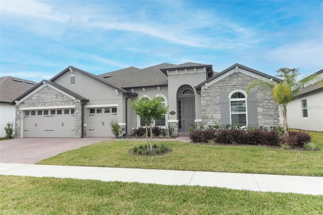 view of front of house featuring stucco siding, stone siding, decorative driveway, a front lawn, and an attached garage