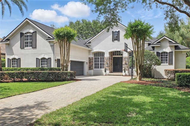 view of front of house featuring a garage, a front yard, stucco siding, and decorative driveway