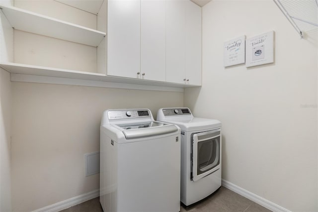 clothes washing area featuring washing machine and dryer, baseboards, light tile patterned flooring, and cabinet space