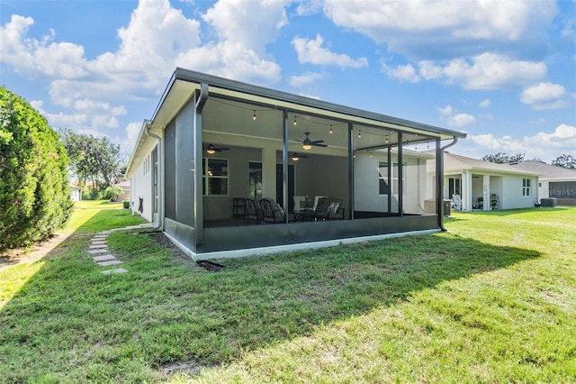 rear view of house with a yard, stucco siding, a sunroom, and ceiling fan