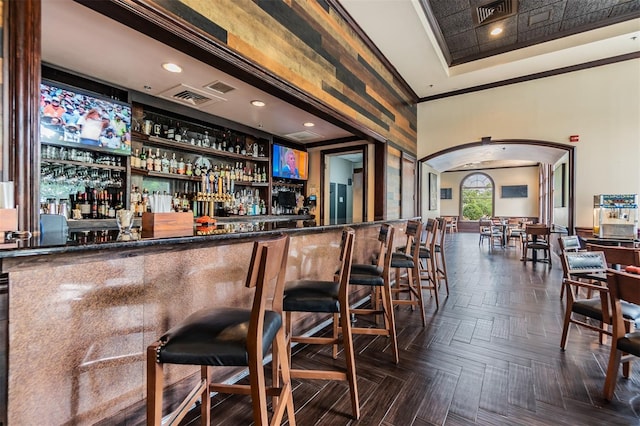 bar with a bar, arched walkways, a tray ceiling, and visible vents