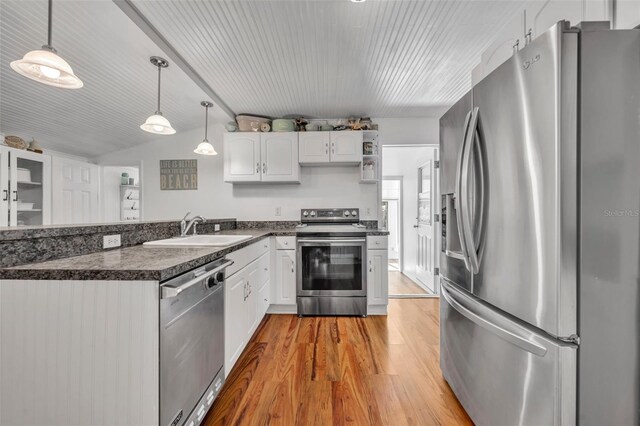 1110 Virginia Ave, Saint Cloud, FL 34769 - kitchen with white cabinets, a sink, dark countertops, a peninsula, and stainless steel appliances