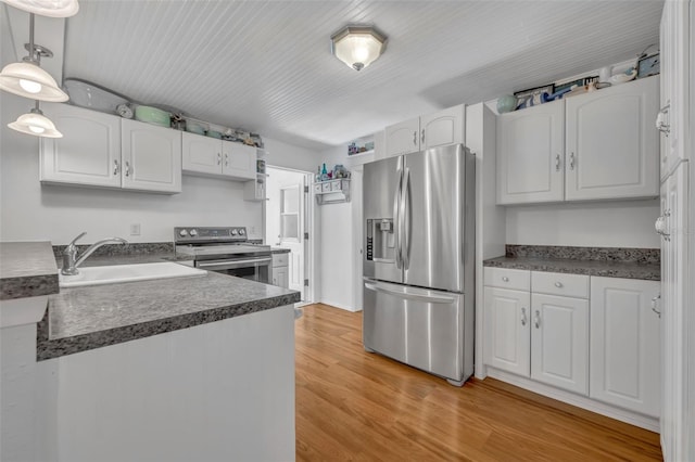 1110 Virginia Ave, Saint Cloud, FL 34769 - kitchen with white cabinets, a sink, light wood-type flooring, dark countertops, and stainless steel appliances