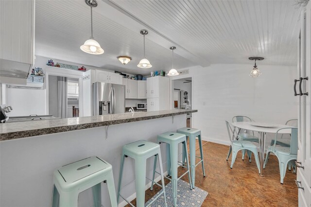 1110 Virginia Ave, Saint Cloud, FL 34769 - kitchen featuring white cabinets, stainless steel refrigerator with ice dispenser, decorative light fixtures, lofted ceiling with beams, and a kitchen breakfast bar