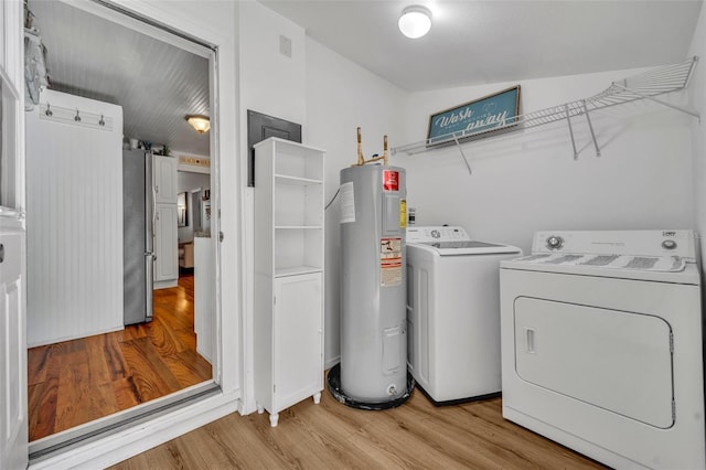 1110 Virginia Ave, Saint Cloud, FL 34769 - clothes washing area featuring electric water heater, independent washer and dryer, laundry area, and wood finished floors