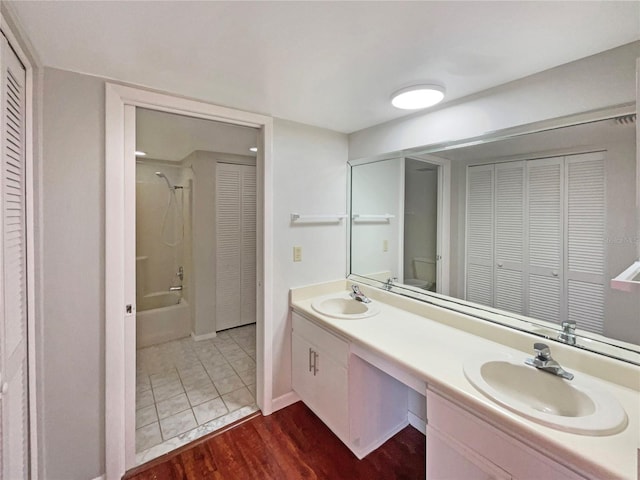 bathroom featuring double vanity, a closet, a sink, and wood finished floors