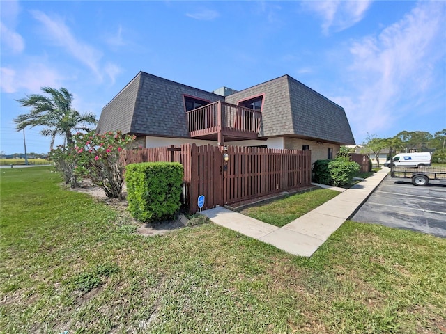 view of property exterior with mansard roof, a shingled roof, fence, and a balcony