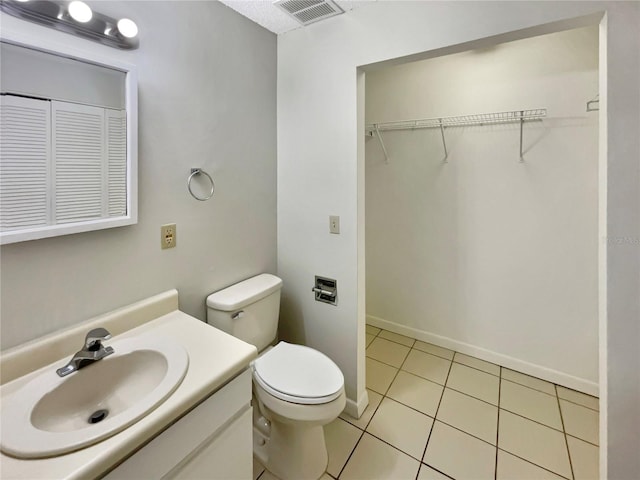 bathroom with visible vents, baseboards, toilet, vanity, and tile patterned flooring
