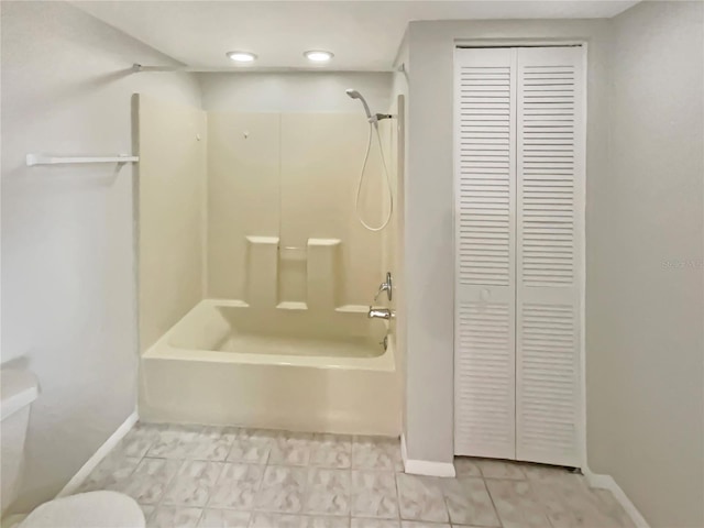 bathroom with a closet, toilet, bathing tub / shower combination, and baseboards