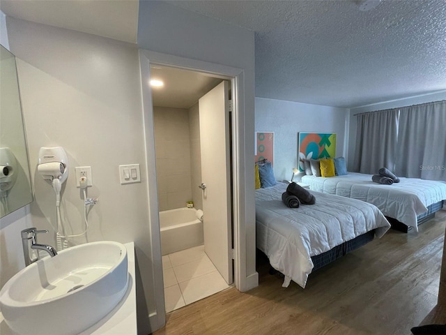 bedroom with a sink, wood finished floors, and a textured ceiling