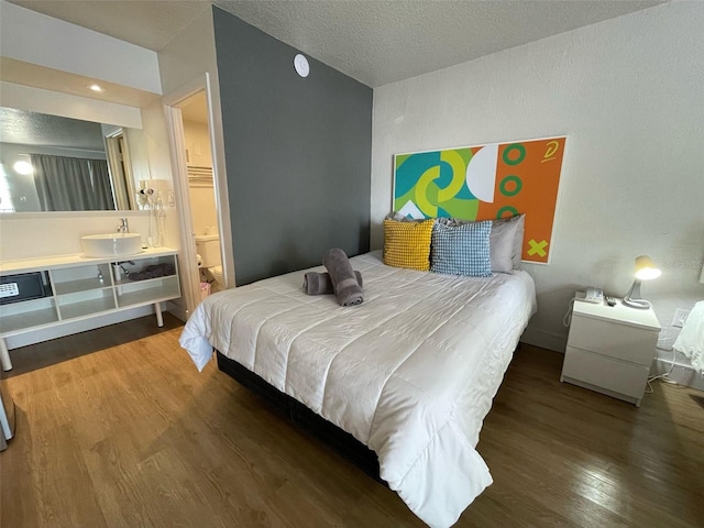 bedroom featuring a textured ceiling, wood finished floors, and ensuite bath