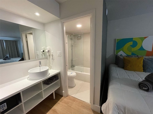bathroom with toilet, recessed lighting, vanity, wood finished floors, and shower / tub combination