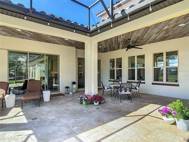 view of patio featuring a ceiling fan and glass enclosure