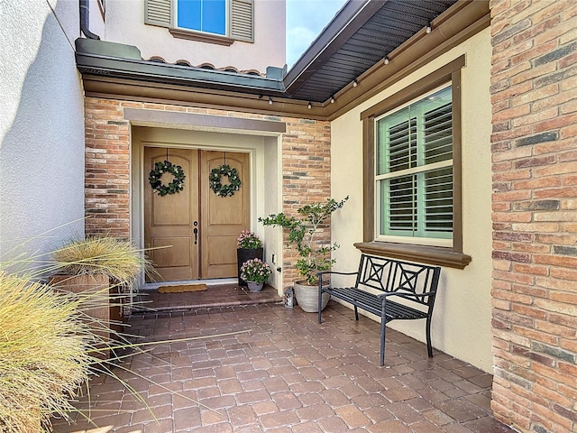 view of exterior entry with brick siding and stucco siding