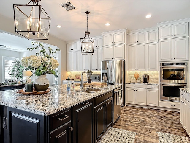 kitchen with an inviting chandelier, dark cabinets, white cabinets, visible vents, and stainless steel appliances