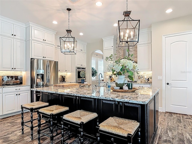 kitchen with white cabinetry, backsplash, appliances with stainless steel finishes, and a chandelier