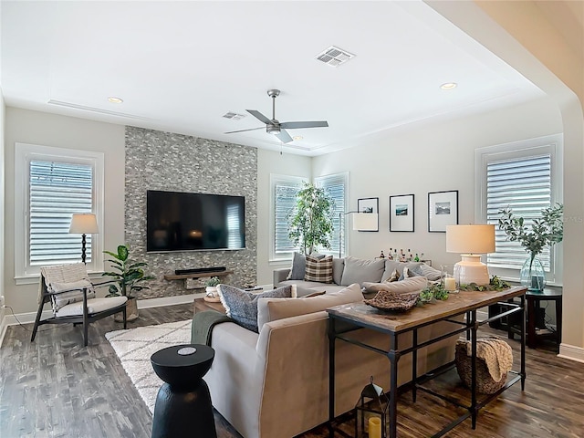 living room featuring wood finished floors, visible vents, ceiling fan, and plenty of natural light
