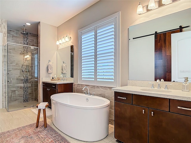 full bathroom featuring a shower stall, a freestanding tub, a sink, and two vanities