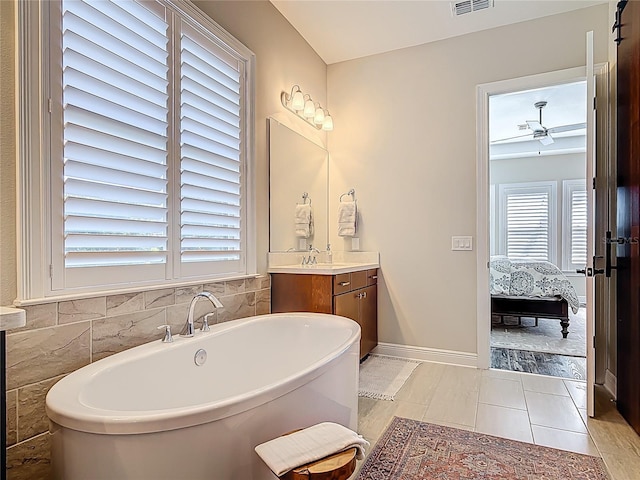 ensuite bathroom featuring ensuite bathroom, a freestanding tub, vanity, tile patterned floors, and baseboards