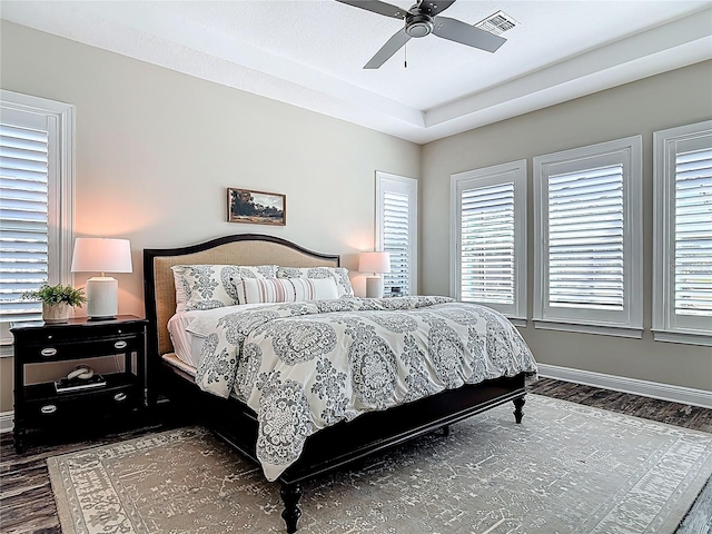 bedroom featuring wood finished floors, baseboards, a ceiling fan, and visible vents