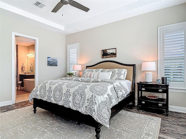 bedroom with wood finished floors, ensuite bathroom, baseboards, and visible vents