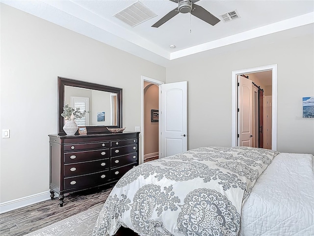 bedroom featuring wood finished floors, baseboards, a ceiling fan, and visible vents