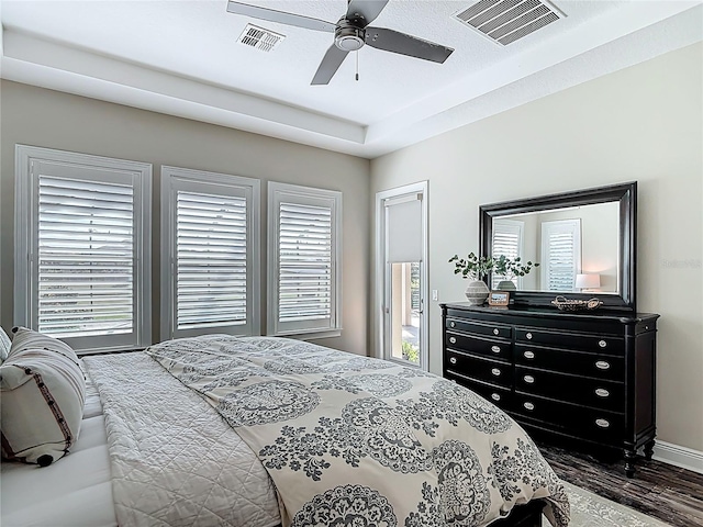 bedroom featuring dark wood-style floors, visible vents, and ceiling fan