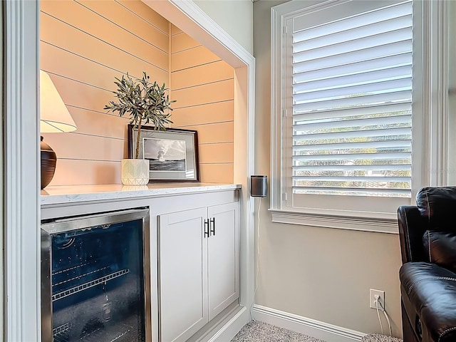 bar featuring wood walls, beverage cooler, baseboards, and a dry bar