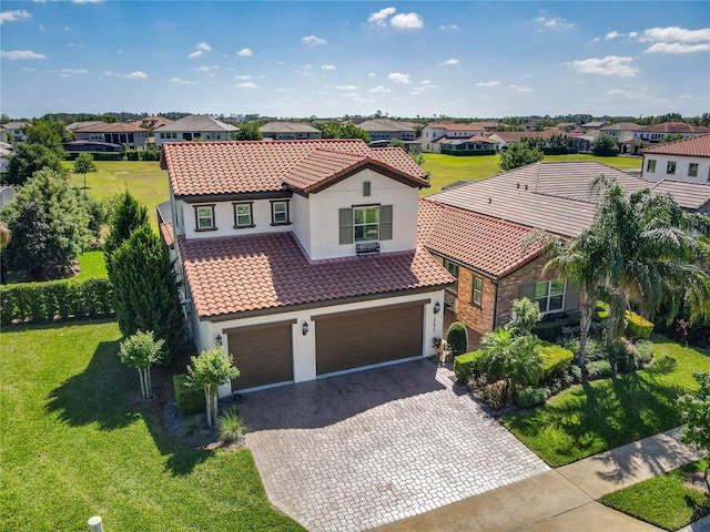mediterranean / spanish-style home featuring an attached garage, a tile roof, stucco siding, a residential view, and decorative driveway