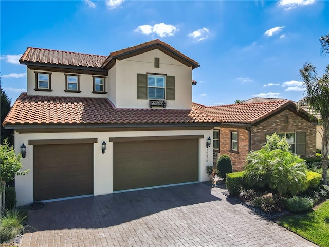 mediterranean / spanish home featuring a tiled roof, a garage, and stucco siding