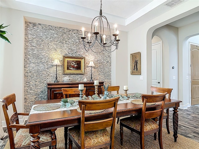dining room featuring arched walkways, visible vents, an inviting chandelier, and wood finished floors