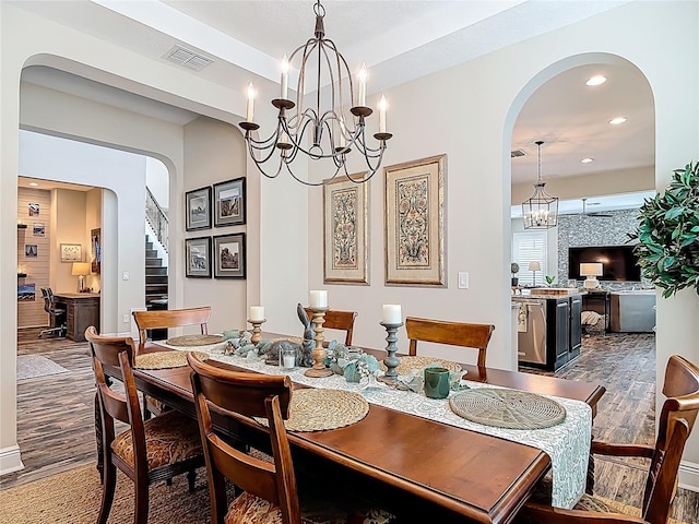 dining area with dark wood finished floors, arched walkways, visible vents, recessed lighting, and a notable chandelier