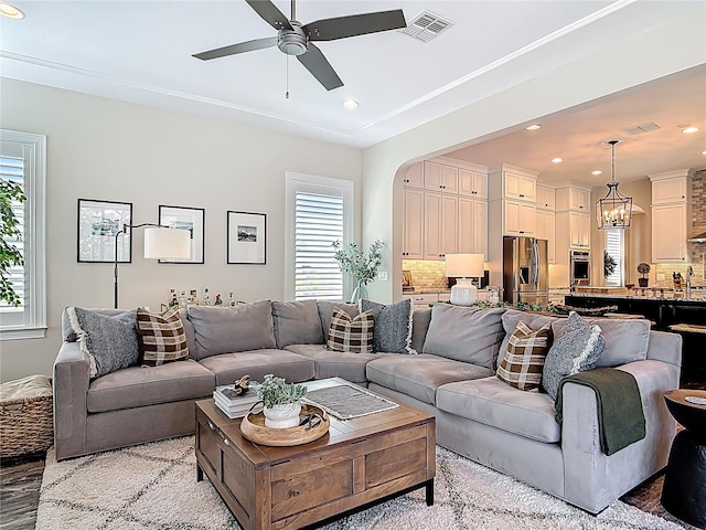 living room featuring ceiling fan with notable chandelier, plenty of natural light, and recessed lighting