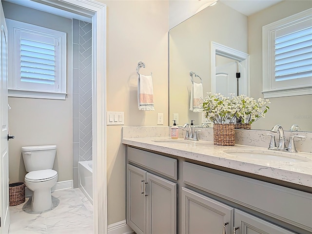 full bathroom with double vanity, marble finish floor, a sink, and toilet