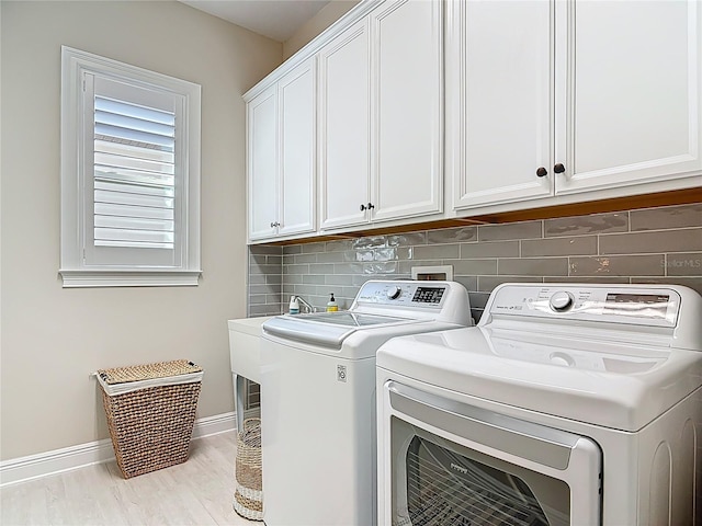clothes washing area with washing machine and dryer, baseboards, and cabinet space