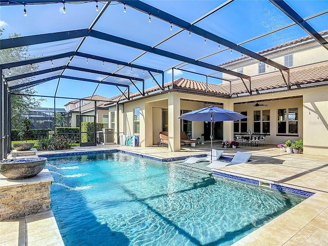 outdoor pool featuring a patio area, a ceiling fan, and glass enclosure