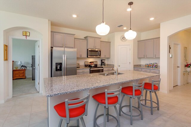 6960 Audobon Osprey Cv, Harmony, FL 34773 - kitchen with gray cabinetry, appliances with stainless steel finishes, a sink, and arched walkways