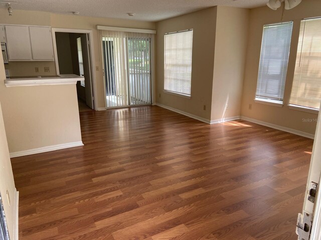 unfurnished living room with baseboards and wood finished floors