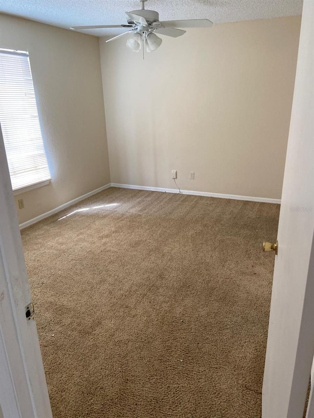 spare room with baseboards, a ceiling fan, carpet flooring, and a textured ceiling